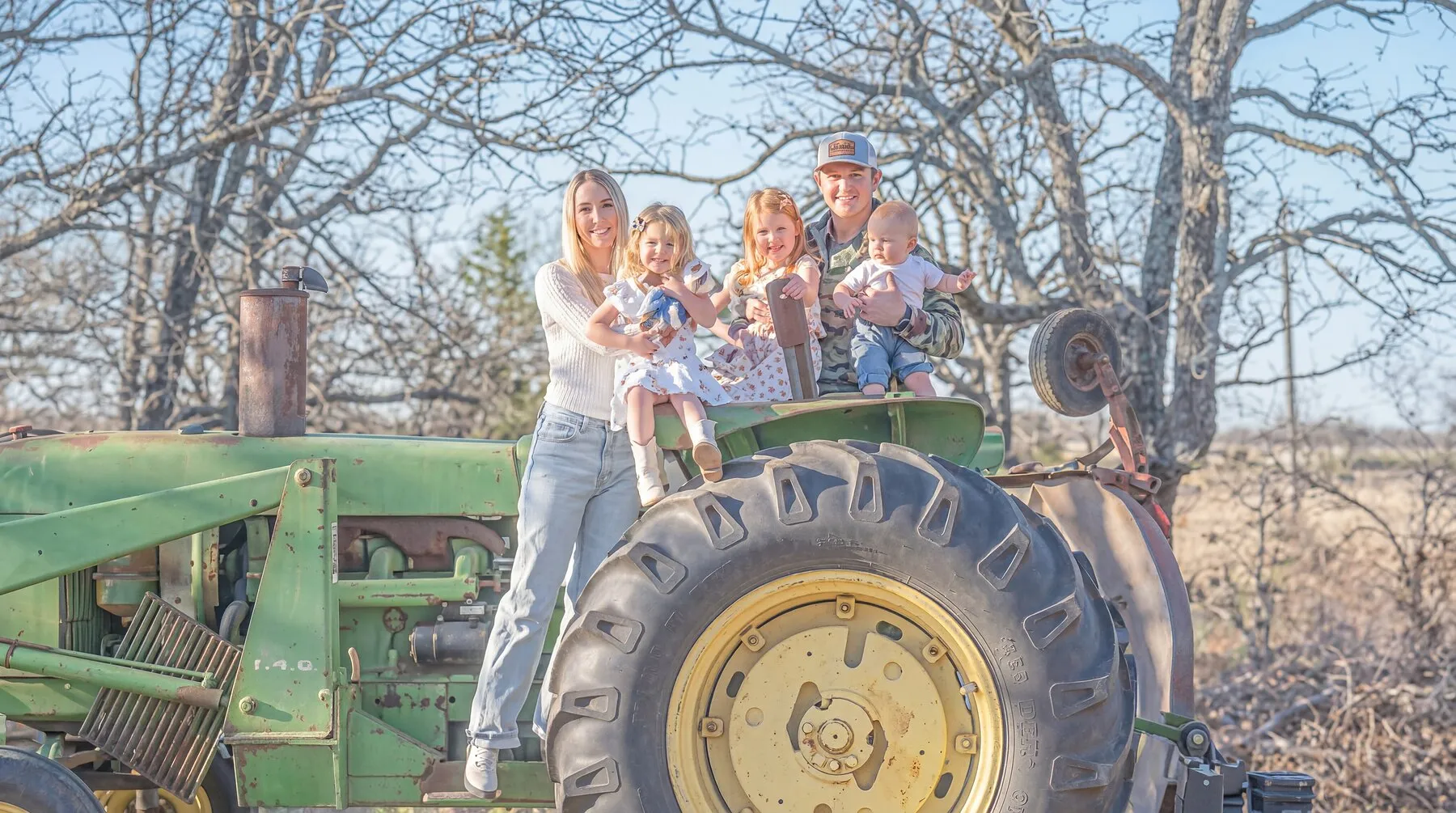 Fort Worth realtor Conner Nielsen with his family on a vintage green tractor at golden hour
